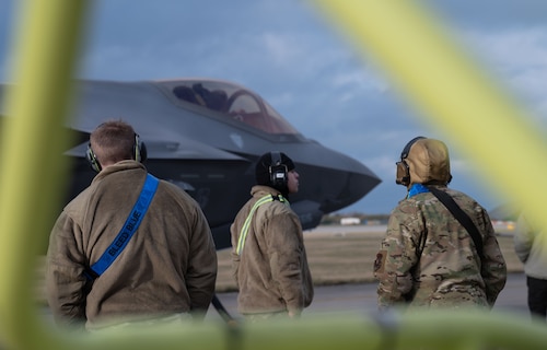 Three people stand next to a plane.