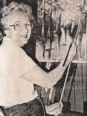 Artist posing while painting a swamp scene.