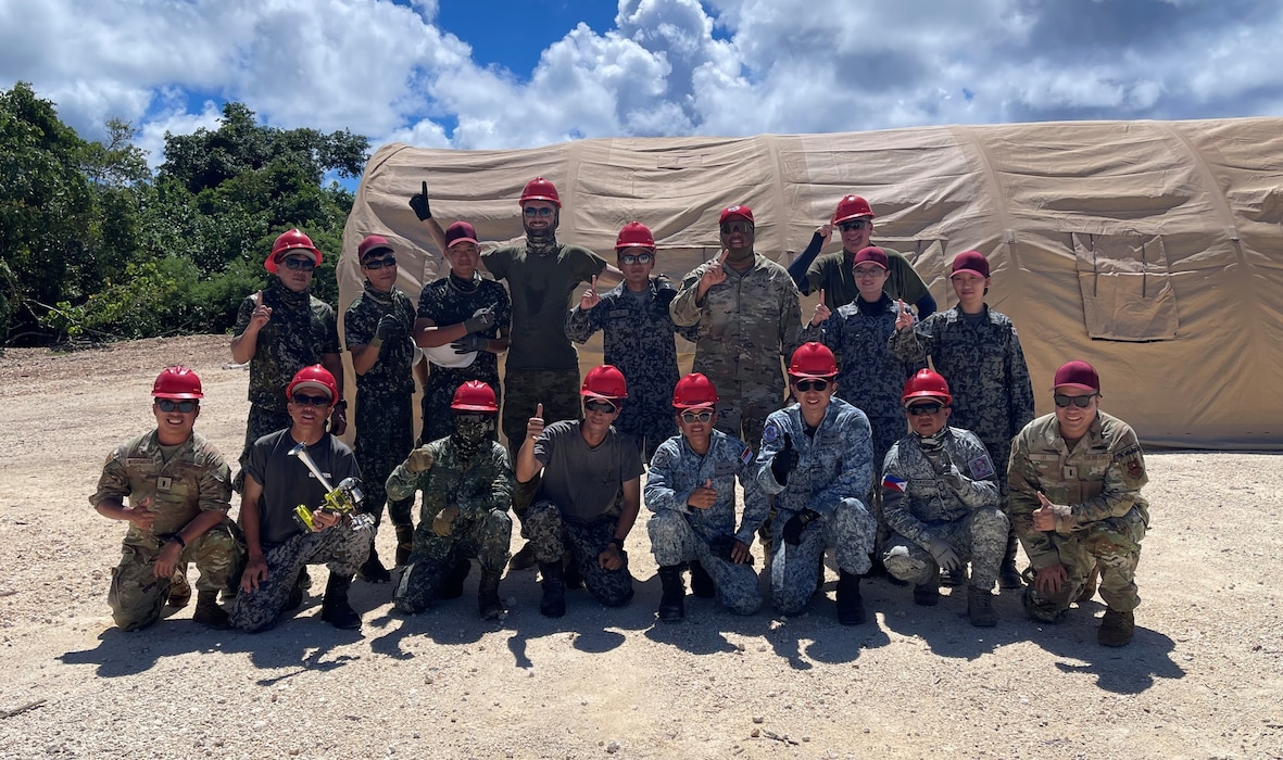 LEAP Scholars 1st Lt. Masahito Nishimura (bottom far left) and 1st Lt. Yu Lei (bottom far right) pose with military members from partner allies, a member of Red Horse, and United States Air Force interpreters after a tent building event during the recent Allies & Partners Engineer Summit in the INDOPACOM AOR.