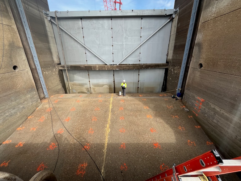 Rebekah Lee, research geophysicist with ERDC's Geotechnical and Structures Lab, standing beside the gravimeter used to accurate measure gravity in the dewatered bay.