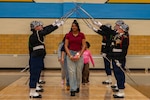 A graduating senior walks beneath a ceremonial saber arch formed by the Cheyenne Central High School Junior ROTC Color Guard during Senior Military Night in Cheyenne, Wyoming, Feb. 17, 2026. The annual ceremony recognizes students who commit to military service after high school. Photo by Senior Airman Michael Swingen.