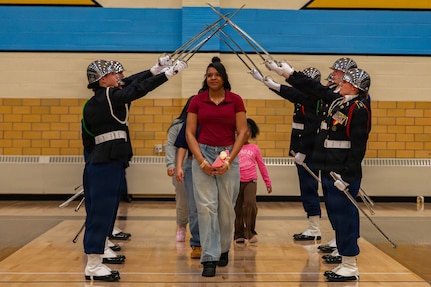 A graduating senior walks beneath a ceremonial saber arch formed by the Cheyenne Central High School Junior ROTC Color Guard during Senior Military Night in Cheyenne, Wyoming, Feb. 17, 2026.
