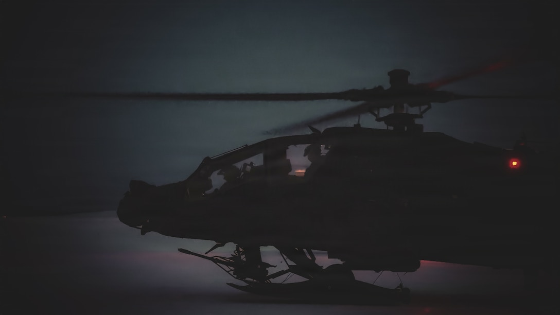 An AH-64 Apache idles on a snow covered flight line while aircrew conduct nighttime aviation operations in support of Joint Pacific Multinational Readiness Center 26-02 at Fort Wainwright, Alaska, Feb. 2026.