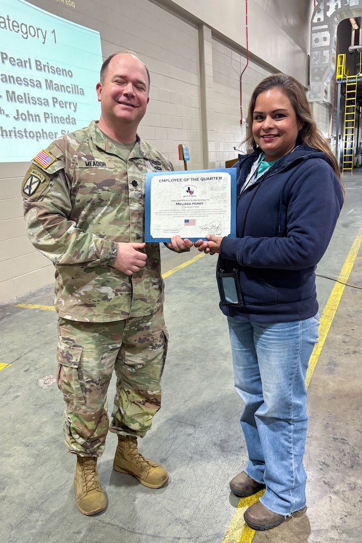 A man wearing a camouflage military uniform poses with another person holding an award certificate.