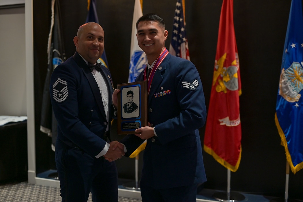 An Air Force senior master sergeant presents a plaque to a senior airman for an award.