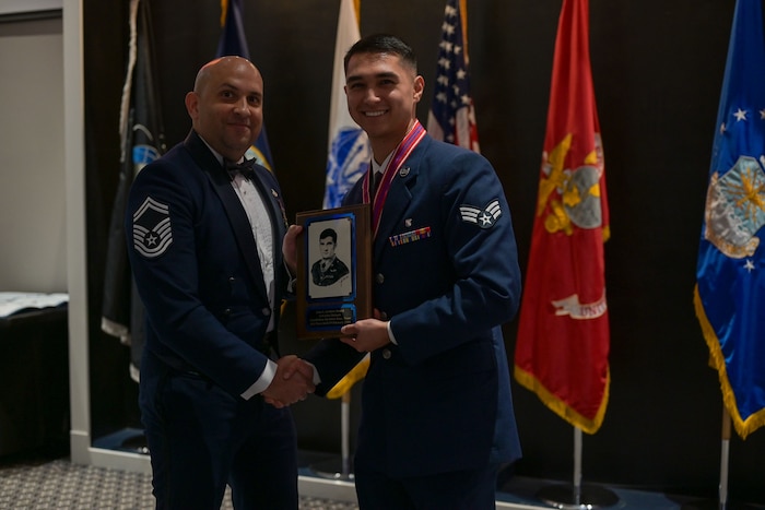 An Air Force senior master sergeant presents a plaque to a senior airman for an award.
