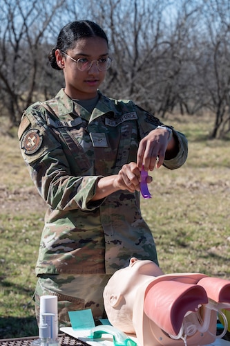 Service member uses a mannequin to demonstrate how to clear an airway.