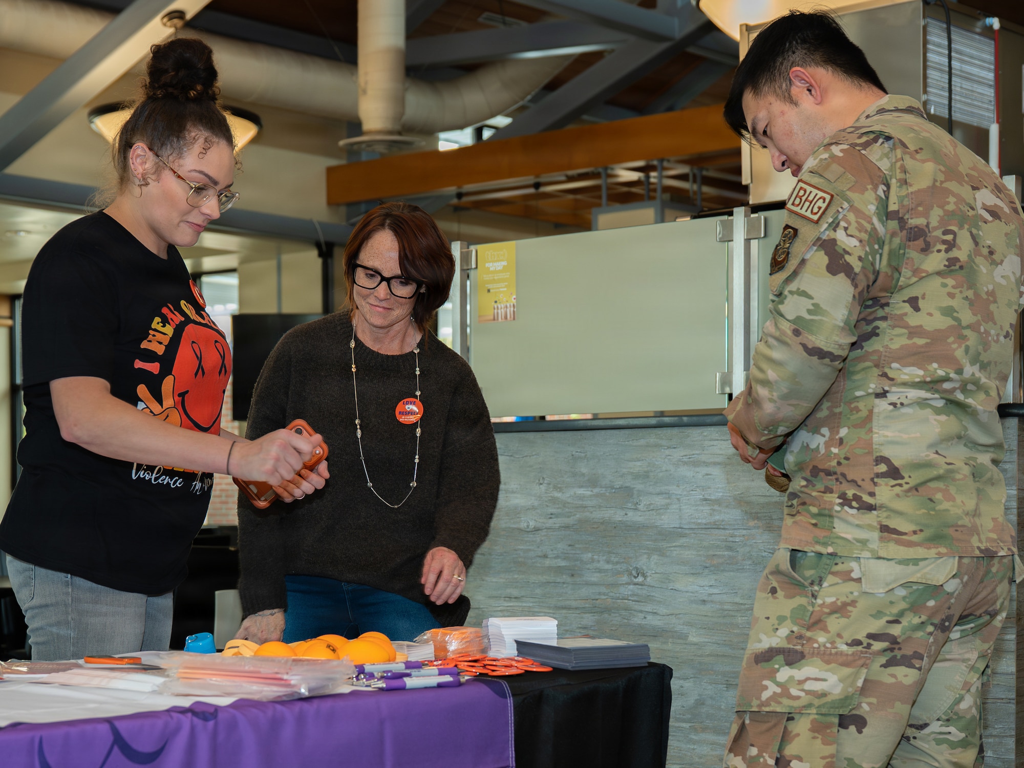 Two civilians from the Integrated Resilience Office discuss with an Airman about teenage dating violence.