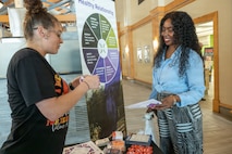 Civilians from Joint Base Charleston have a conversation about teenage dating in front of an infographic