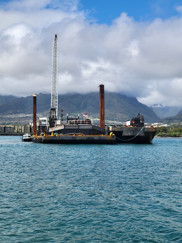 A barge sits with a crane on top of it in the waters of Kahului Harbor, Maui.
