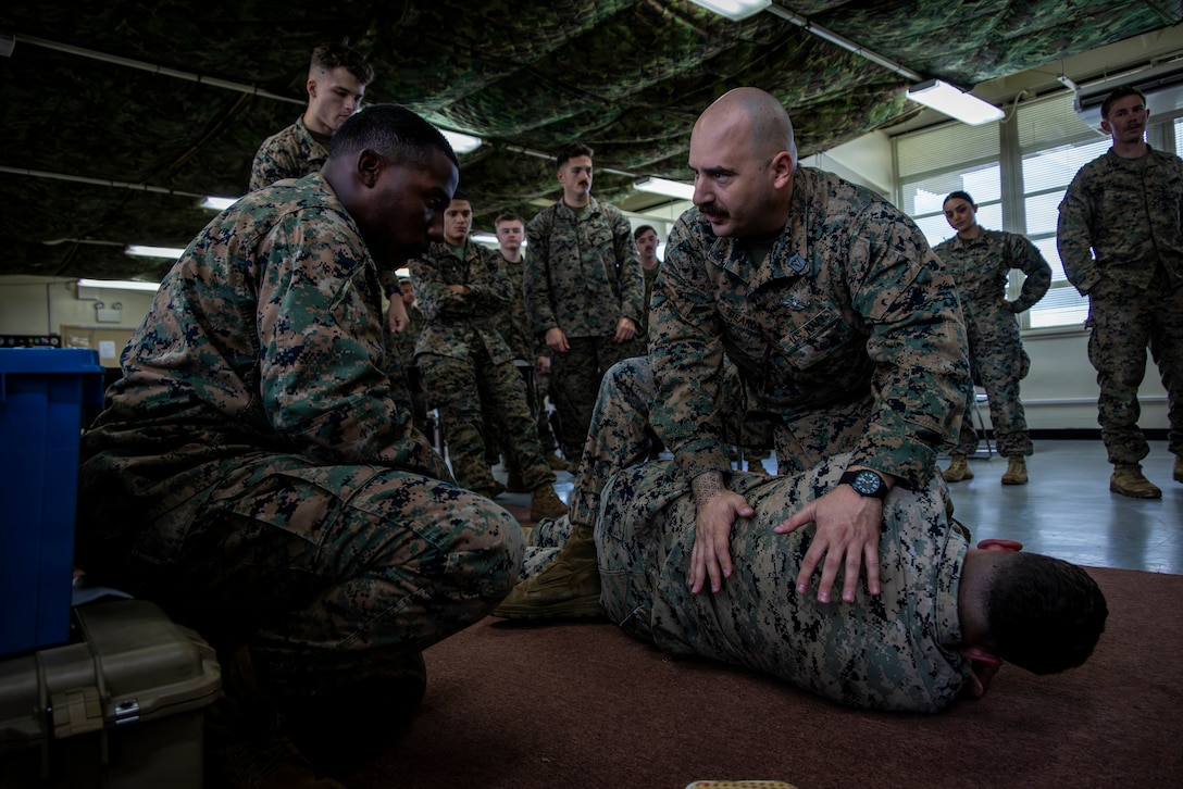 U.S. Navy Hospital Corpsman 1st Class Jonathan Beard, right, a course instructor with Headquarters Company, 3rd Marine Division, explains how to treat a life-threatening chest injury during a Combat Lifesaver Course, Camp Hansen, Okinawa, Japan, Jan. 6, 2025. The 40-hour course prepares Marines to treat wounded service members, prevent additional casualties, and complete their missions while in combat. Beard is a native of California. (U.S. Marine Corps photo by Sgt. Jackson Ricker)