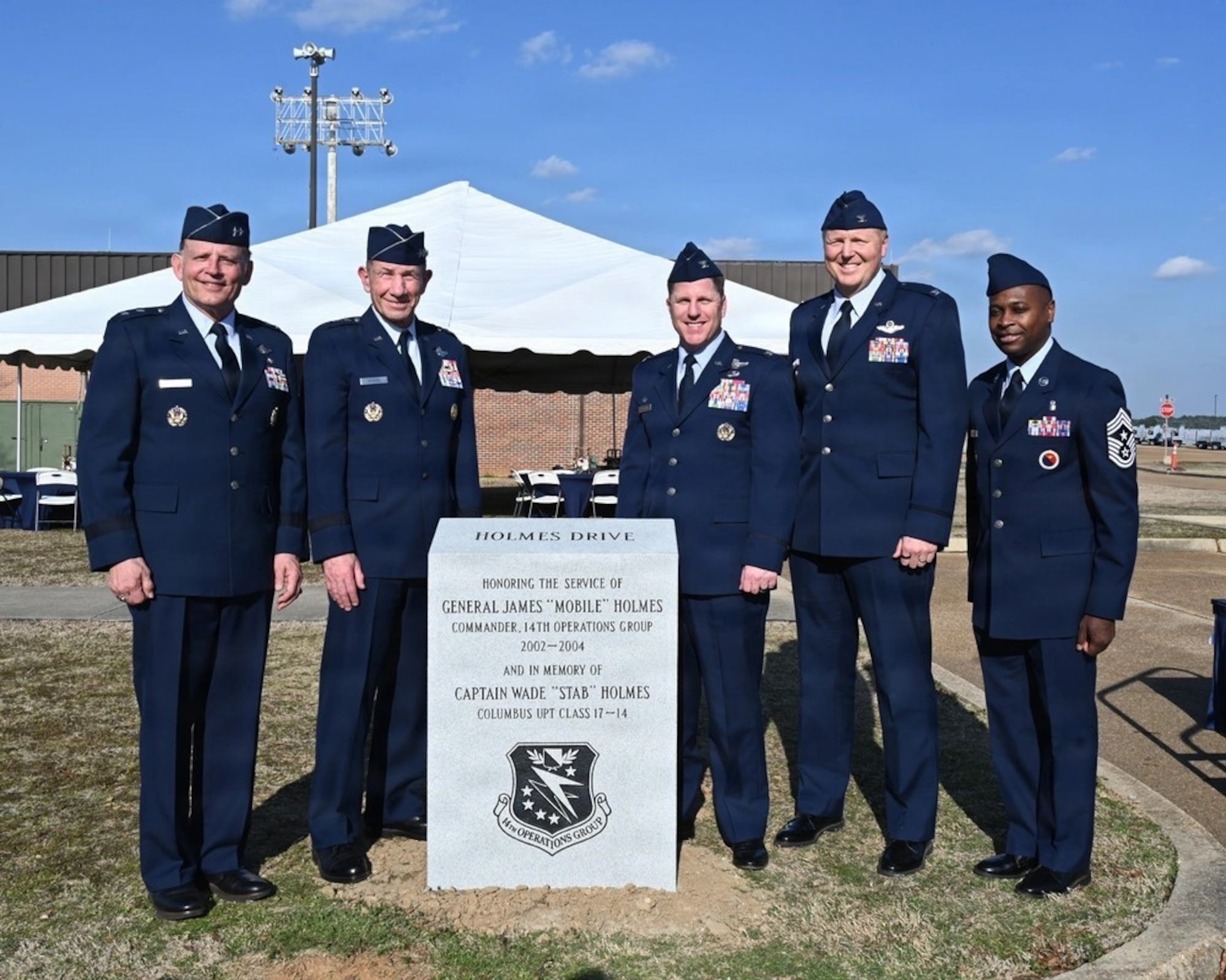 Men in uniform stand beside a new memorial plaque.