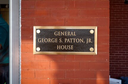 Dark brown plaque with brass trim on a red brick wall that reads "General George S. Patton, Jr. House"