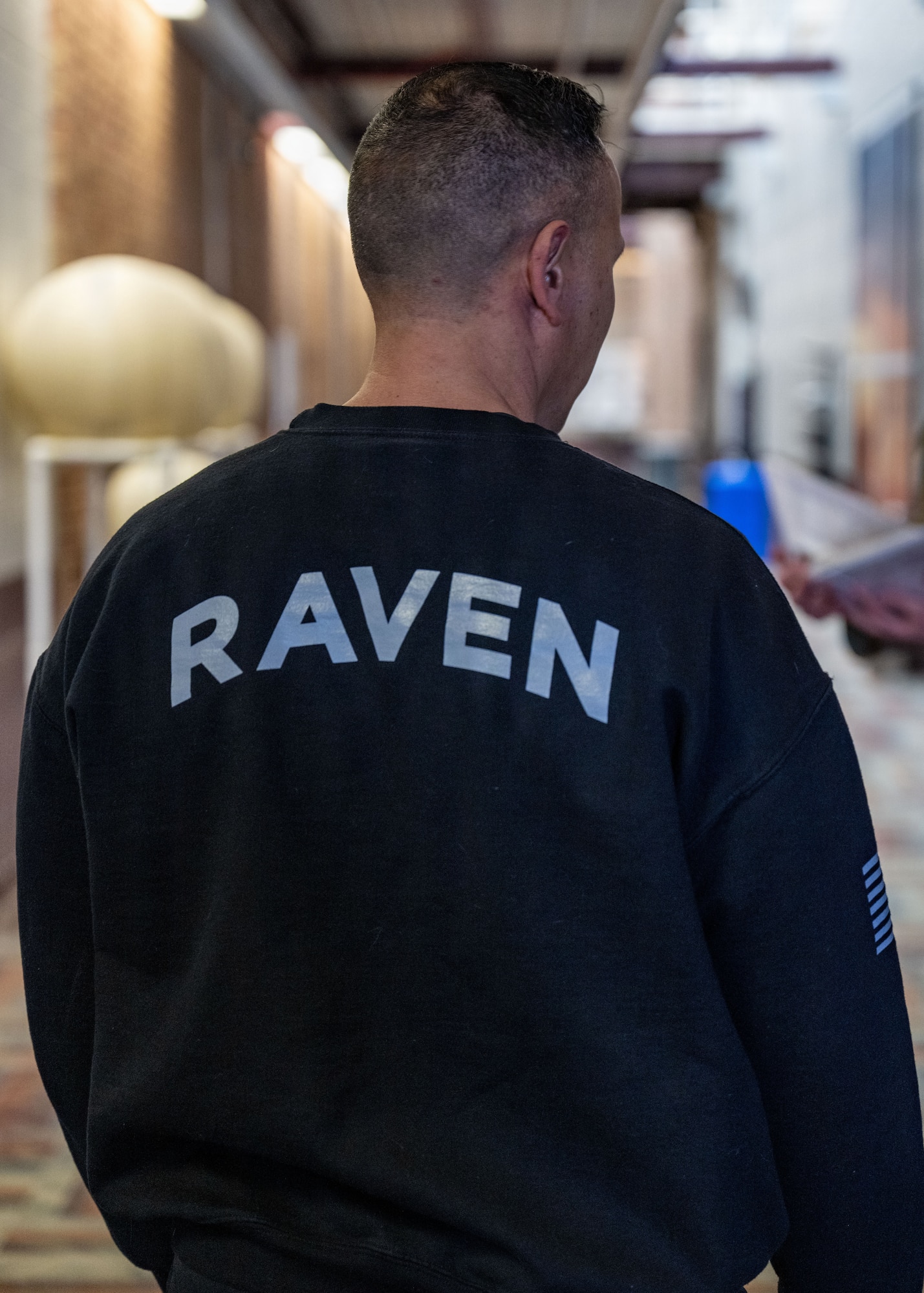 A man in a Raven sweatshirt stands.
