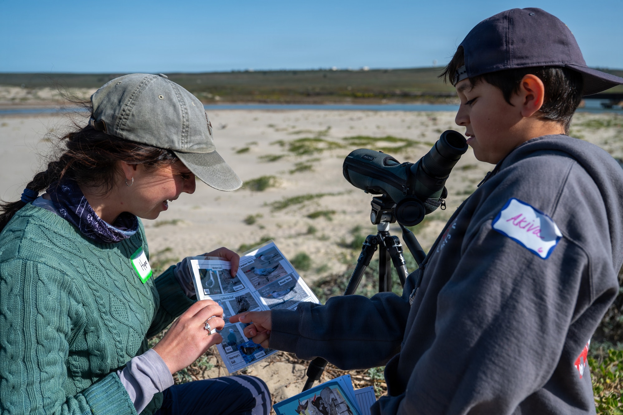 Hope Caliendo, left, Point Blue Conservation coastal biologist, shows a bird field guide to a student, right, from Lompoc Unified School District during a wildlife education field trip at Ocean Park in Lompoc.