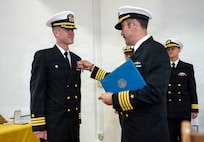 U.S. Navy Capt. David Huljack, commanding officer of Destroyer Squadron (DESRON) 15, right, presents a Meritorious Service Medal to Cmdr. Paul Archer, off-going commanding officer of Arleigh Burke-class guided-missile destroyer USS Preble (DDG 88) during a change of command ceremony at Commander, Fleet Activities Yokosuka Headquarters’ C-2 Auditorium in Yokosuka, Japan, Feb. 20, 2026.