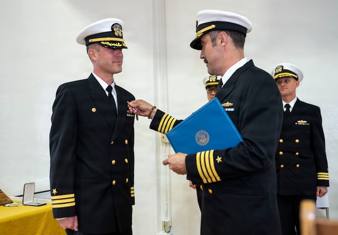 U.S. Navy Capt. David Huljack, commanding officer of Destroyer Squadron (DESRON) 15, right, presents a Meritorious Service Medal to Cmdr. Paul Archer, off-going commanding officer of Arleigh Burke-class guided-missile destroyer USS Preble (DDG 88) during a change of command ceremony at Commander, Fleet Activities Yokosuka Headquarters’ C-2 Auditorium in Yokosuka, Japan, Feb. 20, 2026.