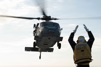 Boatswains Mate 2nd Class Bryce Houck communicates to the pilots of a MH-60S Seahawk helicopter assigned to the “Golden Falcons” of Helicopter Sea Combat Squadron (HSC) 12 during flight quarters aboard U.S. 7th Fleet flagship USS Blue Ridge (LCC 19) in Sagaimi Wan, Feb. 19, 2026.