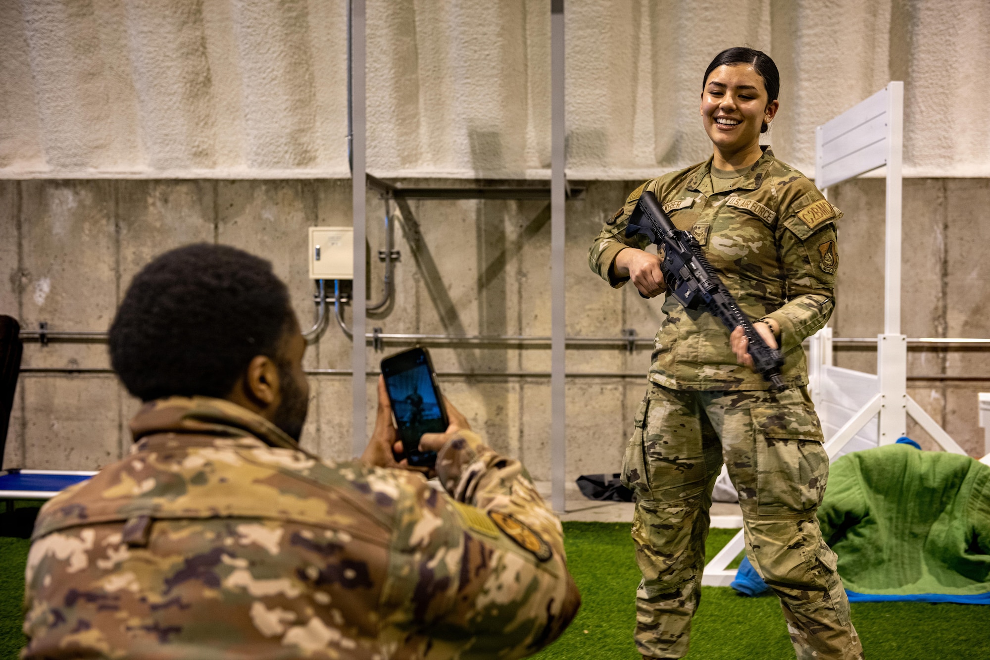 U.S. Air Force Airman 1st Class Mikayla Weber, right, 610th Air Control Flight (ACF) battle management technician, poses with a GAU-5A aircrew self-defense weapon for a photo taken by Senior Airman Xavier Tanner, 610th ACF weapons director, during an immersion tour.