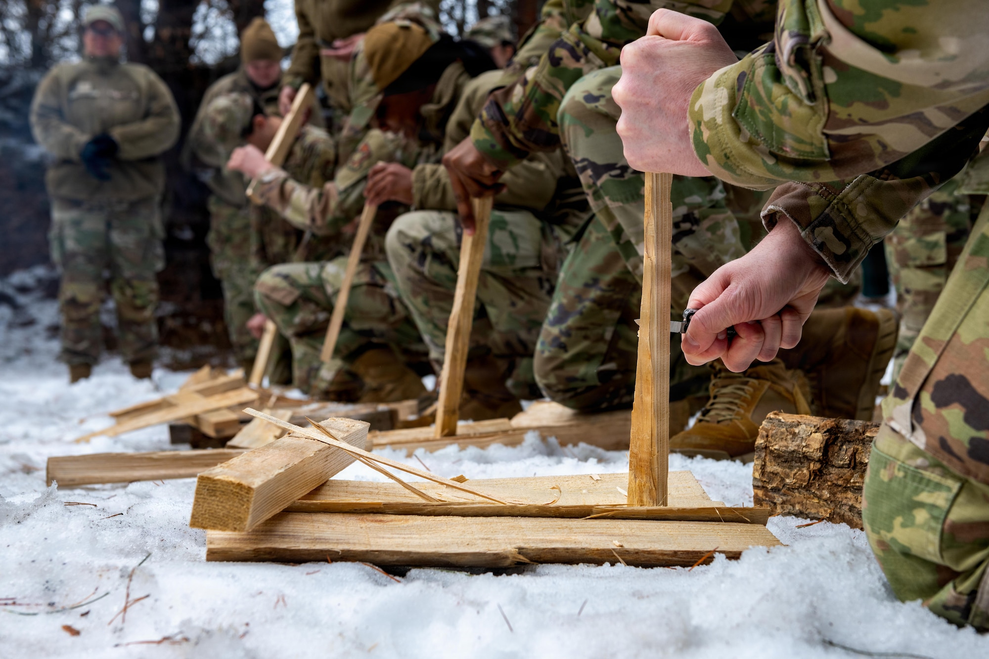 U.S. Airmen assigned to the 35th Fighter Wing practice making feathered sticks to create a campfire during an immersion tour.