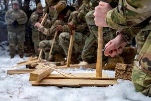 U.S. Airmen assigned to the 35th Fighter Wing practice making feathered sticks to create a campfire during an immersion tour.