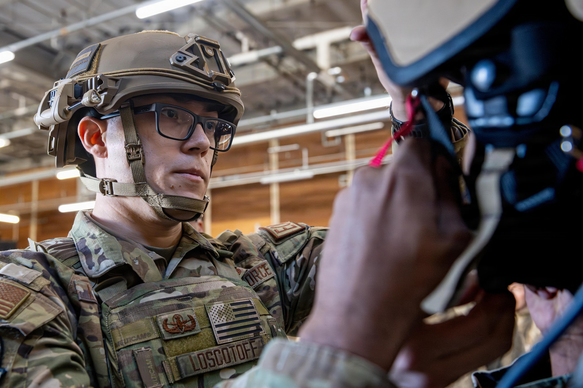 U.S. Air Force Staff Sgt. Anthony Loscotoff, 35th Civil Engineer Squadron noncommissioned officer of explosive ordnance disposal (EOD) training, shows an Airman how to put on an EOD 10E bomb suit helmet during an immersion tour.