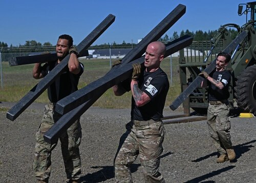 U.S. Air Force Staff Sgt. Ashley Royal, left, ramp operations supervisor, Tech. Sgt. Michael Harrison, center, air terminal operation center senior controller, and Staff Sgt. Seth Dolan, air terminal operation center information controller, all with the 62d Aerial Port Squadron, carry posts on and off a forklift during the Port Dawg Rodeo at Joint Base Lewis-McChord, Washington, June 24, 2022.