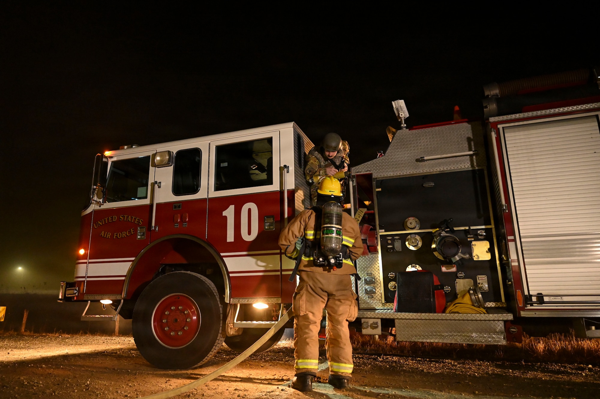 Fire fighters stage fire suppression equipment.