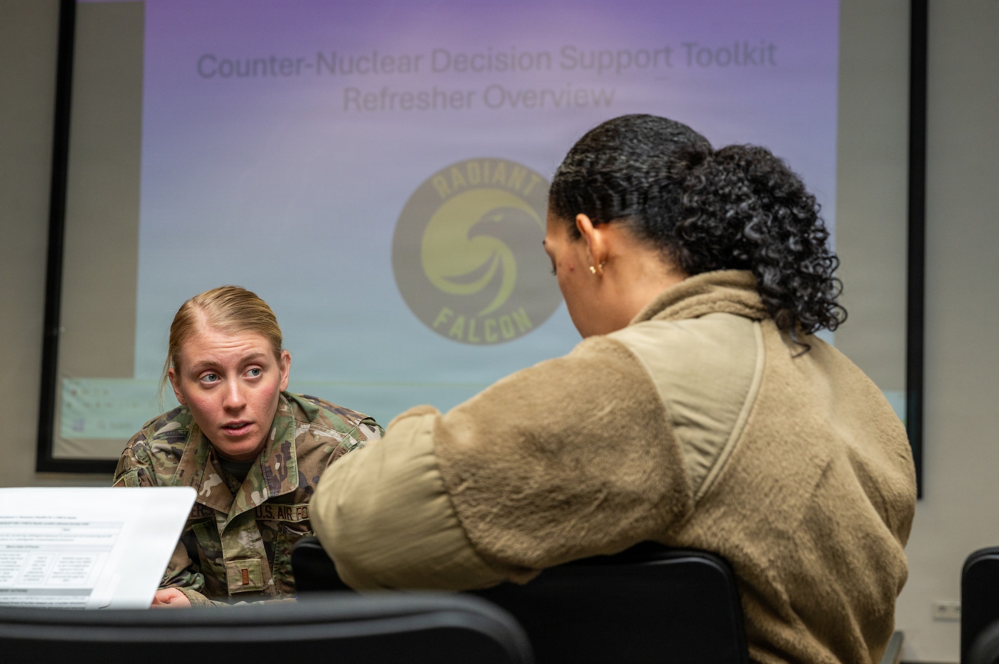 U.S. Air Force 2nd Lt. Allyson Peterson, 86th Operational Medical Readiness Squadron bioenvironmental flight officer in charge, discusses hypothetical decontamination procedures with Airman 1st Class Ceara Williams, 86th OMRS bioenvironmental flight technician, during exercise Radiant Falcon at Ramstein Air Base, Germany, Feb. 12, 2026.