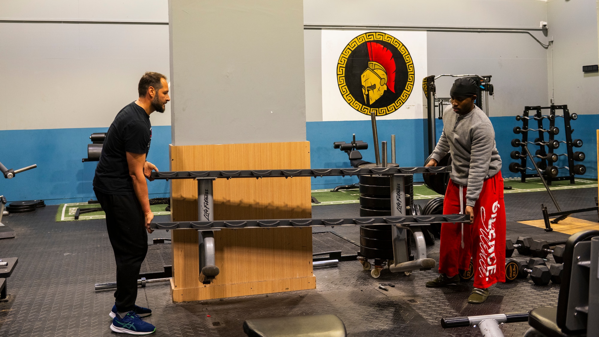 A Spanish Army soldier and a U.S. Airman move a weight rack