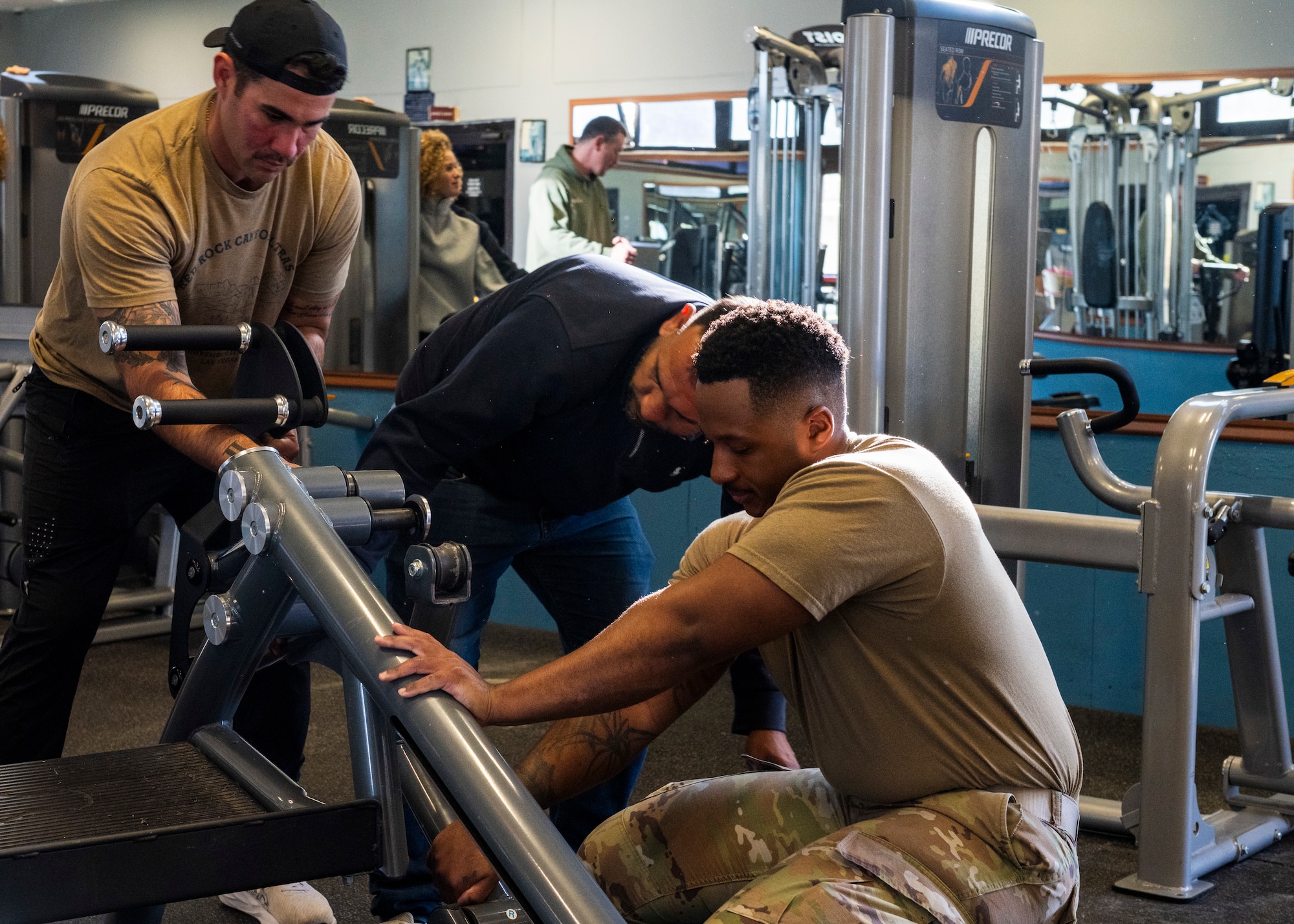 U.S. Airmen and personnel disassemble a strength-training machine