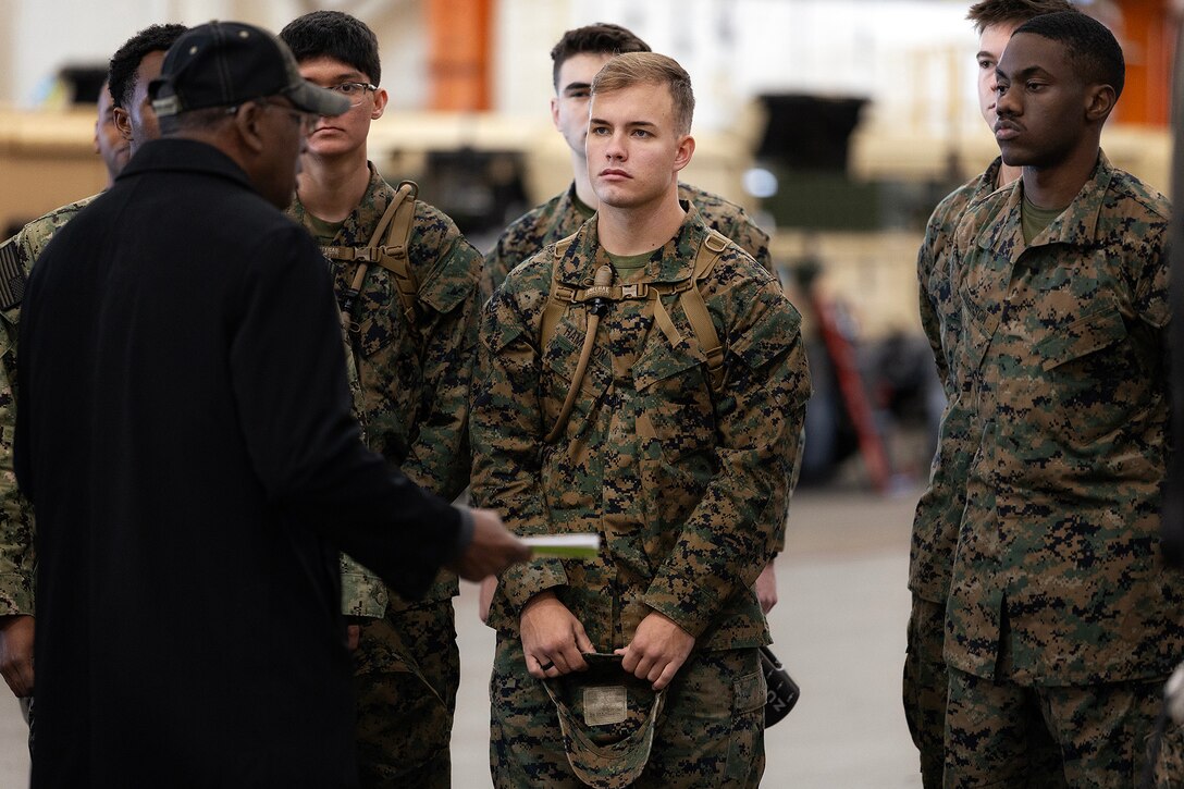 Midshipman 2nd Class Caedon Hampton of Groveland, Florida, listens as retired Marine Corps Maj. Thurman Bobbett, head of the maintenance branch at Blount Island Command, explains corrective and preventive procedures Feb. 23, 2026, inside a warehouse at Marine Corps Support Facility Blount Island, Florida. Students toured the installation to observe lifecycle sustainment of Marine Corps prepositioned equipment. (Official Marine Corps photo by Dustin Senger)