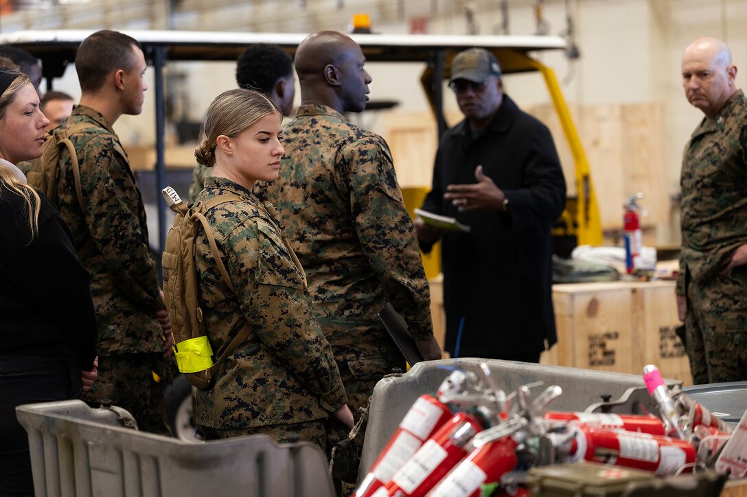 Naval Reserve Officer Training Corps students listen during a corrective and preventive procedures overview with retired Marine Corps Maj. Thurman Bobbett, head of the maintenance branch at Blount Island Command, inside a warehouse Feb. 23, 2026, at Marine Corps Support Facility Blount Island, Florida. The visit provided midshipmen firsthand exposure to how Marine Corps equipment is maintained and staged for expeditionary operations. (Official Marine Corps photo by Dustin Senger)