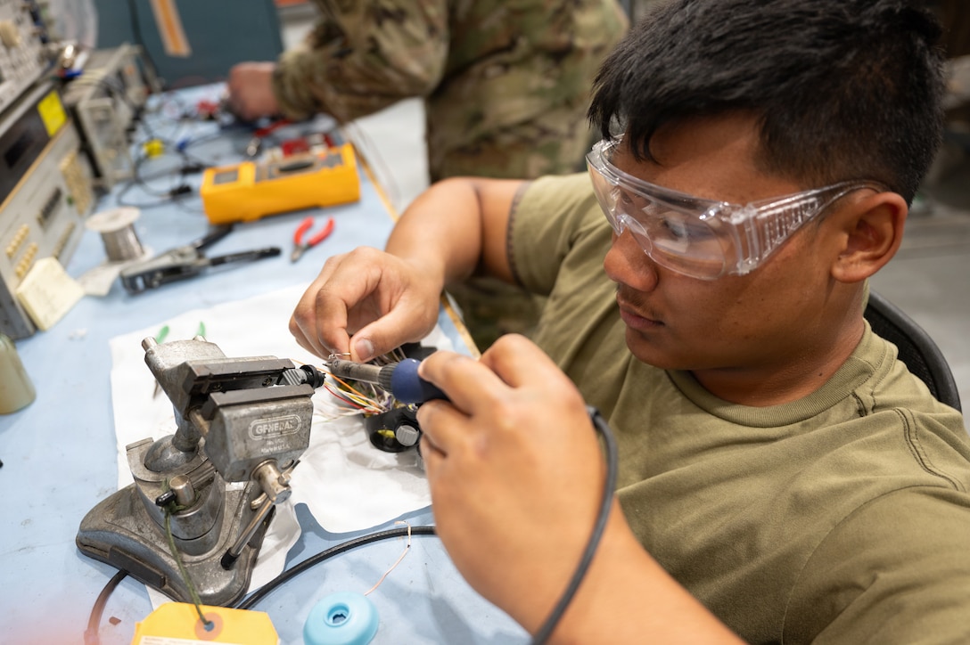 U.S. Air Force Airman 1st Class Elias Aurello, 379th Expeditionary Maintenance Squadron avionics technician, solders wires to an F-16 Fighting Falcon throttle control at Al Udeid Air Base, Qatar, Feb. 18, 2026. Avionics technicians inspect, test, troubleshoot and repair electronic aircraft systems. (U.S. Air Force photo by Tech. Sgt. Chris Thornbury)