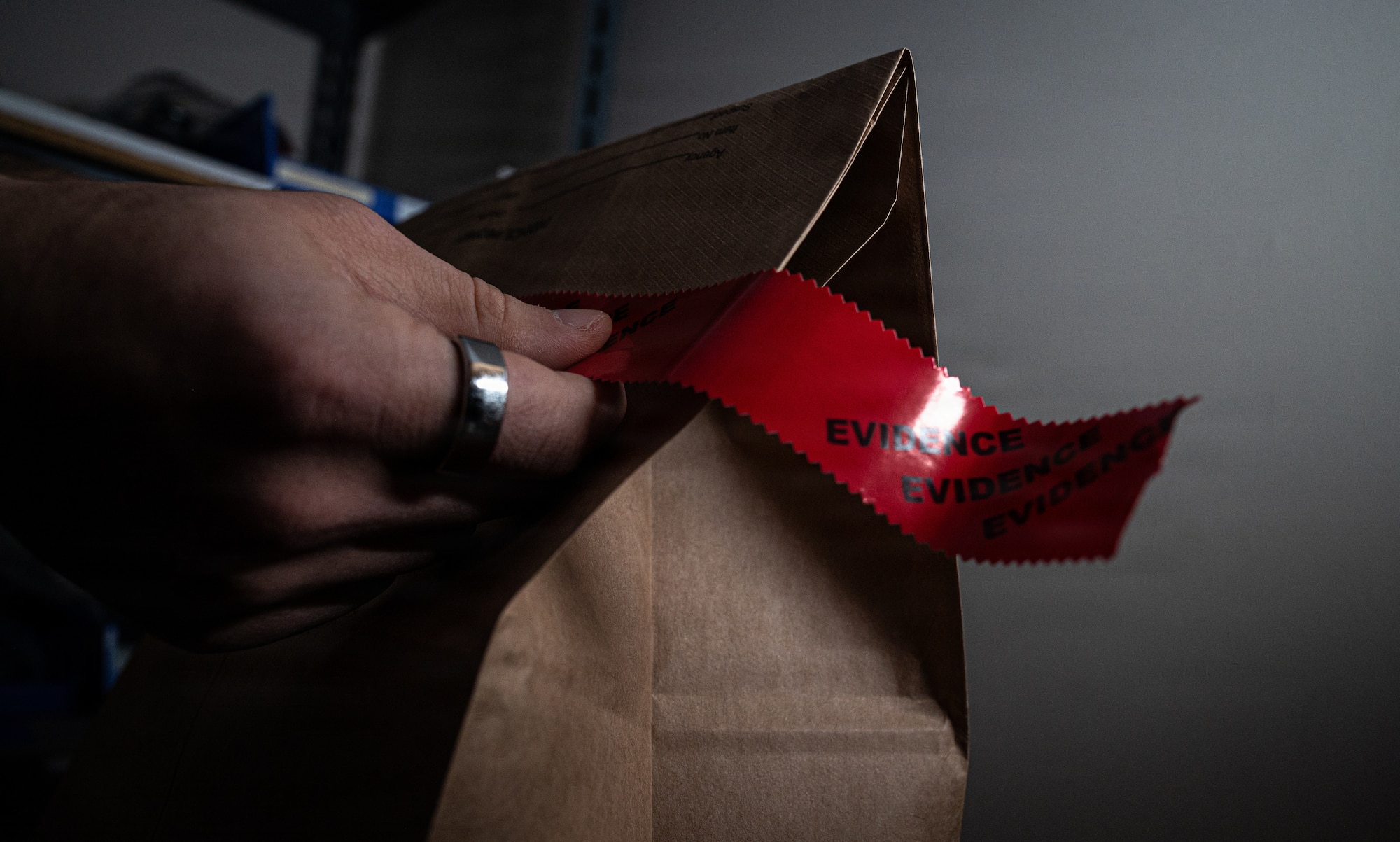 A U.S. Air Force Office of Special Investigations special agent stands near an AFOSI emblem and photos honoring fallen agents during a staged photo at Seymour Johnson Air Force Base, North Carolina, Feb. 11, 2026. AFOSI special agents serve worldwide to protect the Air Force and seek the truth in support of national defense. (U.S. Air Force photo by Airman 1st Class Holly Leonard)