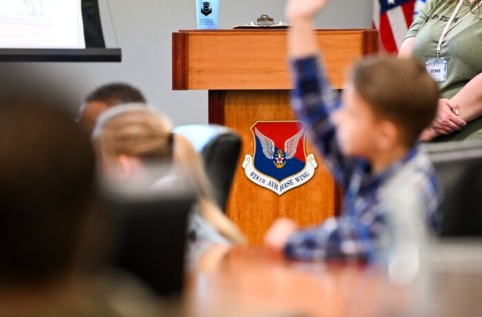 Military homeschoolers of the Lowcountry students raise their hands to ask questions regarding naval service during a wing leadership building tour at Joint Base Charleston.