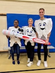 Three dentists stand in an auditorium posing with a giant inflatable toothbrush