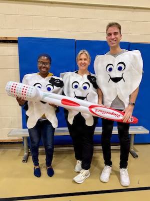 Three dentists stand in an auditorium posing with a giant inflatable toothbrush