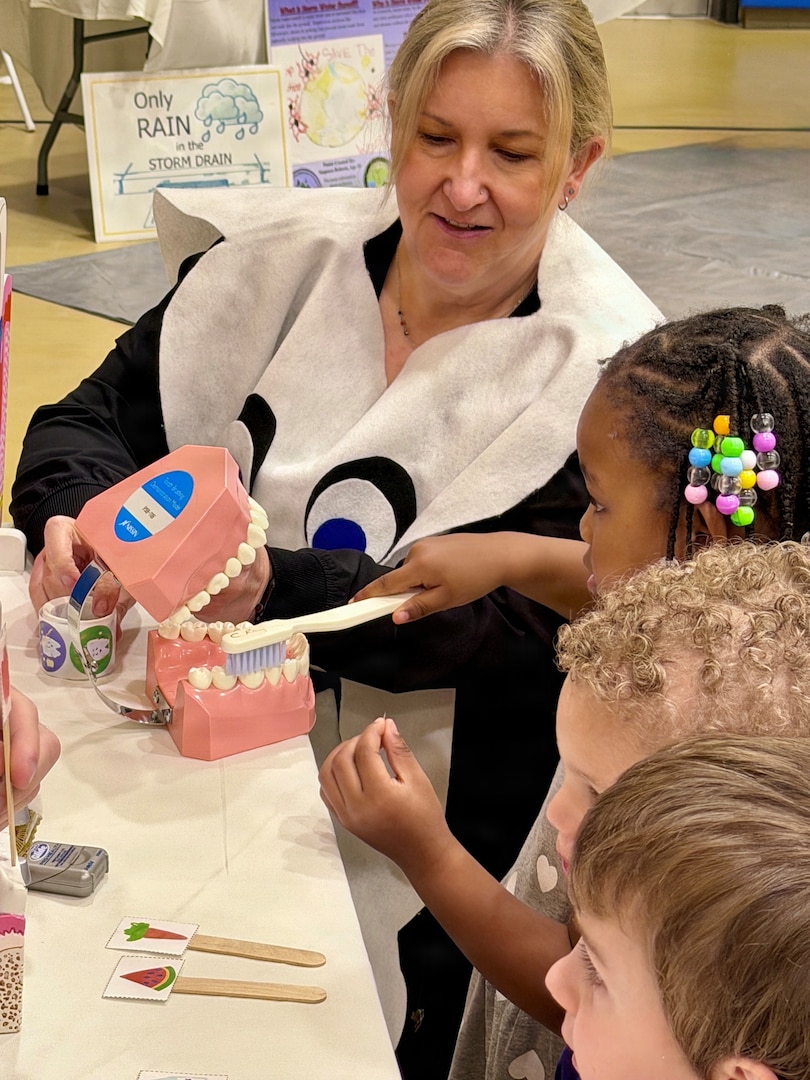 A dental hygienist dressed as a tooth teaches children proper brushing techniques.