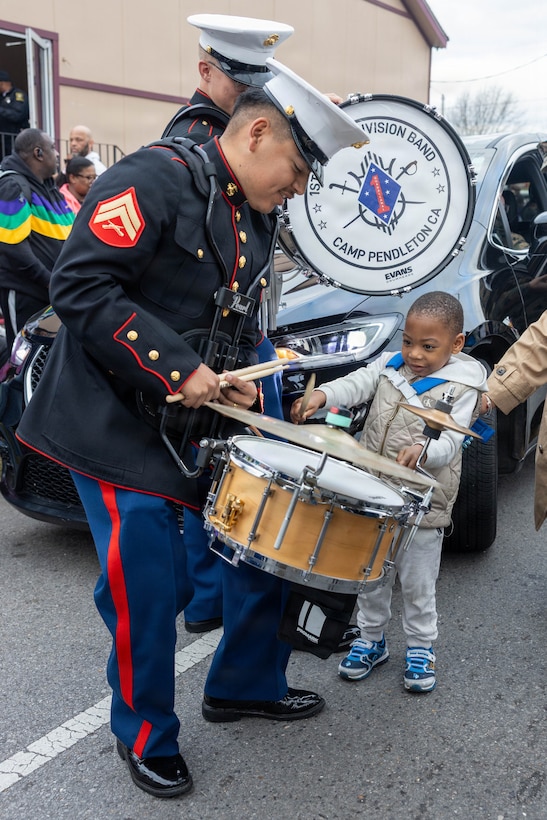 U.S. Marine Corps Cpl. Arturo Tellez, a percussion instrumentalist with the 1st Marine Division Band, interacts with families during the Zulu Mardi Gras Parade as part of the Mardi Gras celebration in New Orleans, Feb. 17, 2026.
