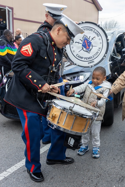 U.S. Marine Corps Cpl. Arturo Tellez, a percussion instrumentalist with the 1st Marine Division Band, interacts with families during the Zulu Mardi Gras Parade as part of the Mardi Gras celebration in New Orleans, Feb. 17, 2026.