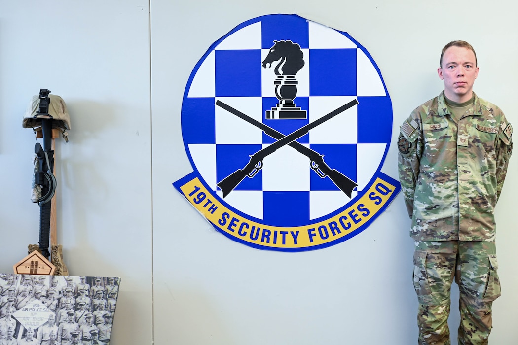 Man poses in front of logo.