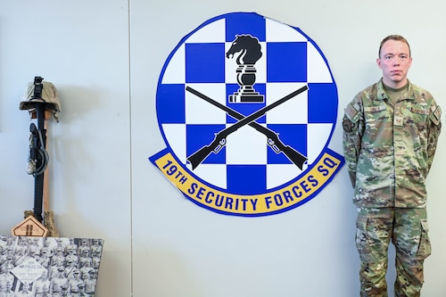 Man poses in front of logo.
