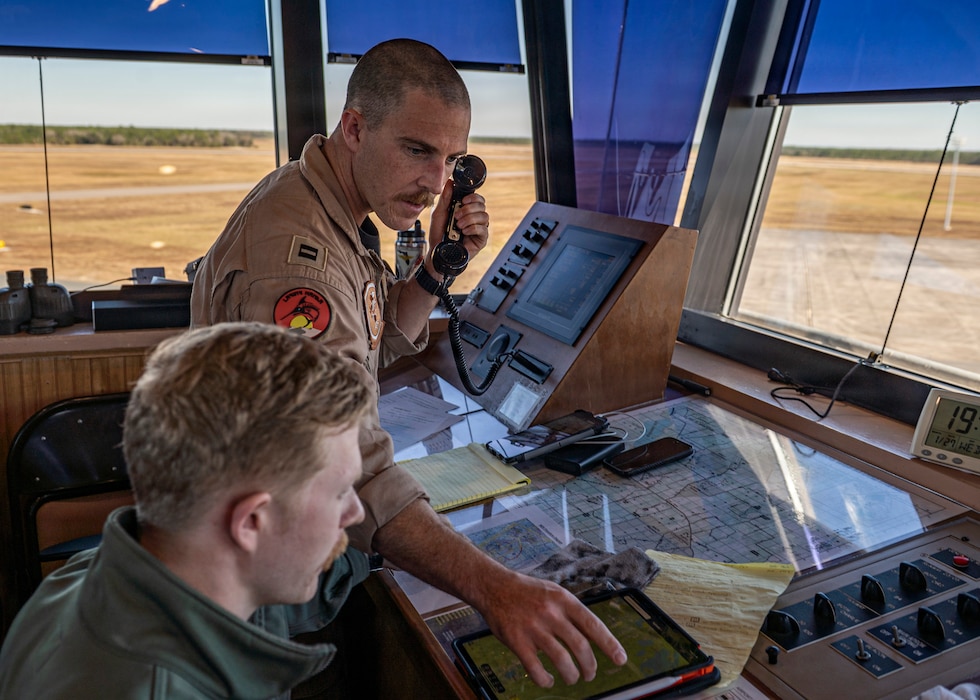 U.S. Navy Lt. Dalton Fletcher, left, an instructor pilot assigned to Training Air Wing (TW-5) FIVE points at a map to U.S. Navy Ens. Duncan Miller, student naval aviator assigned to the “Doerbirds” Training Squadron (VT) 2 at Avon Park Air Force Range, Florida, Jan. 27, 2026. The training was part of a five-week joint primary naval aviation training detachment at the Air Force range. (U.S. Air Force photo by Senior Airman Leonid Soubbotine)