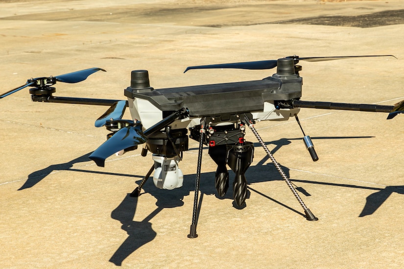 A drone sits on a paved surface outside.