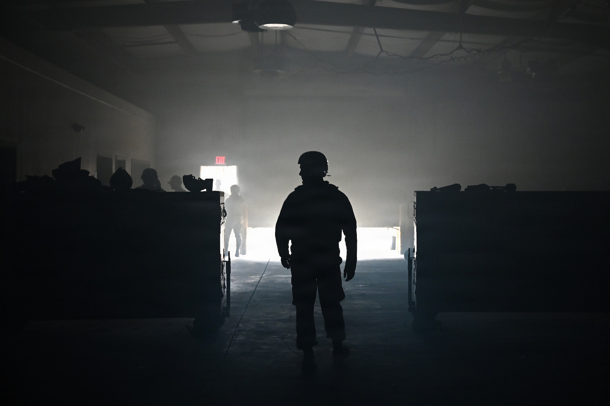 photo silhouette of an air force Airmen inside a dark warehouse with some light creeping behind him
