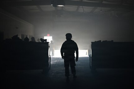 photo silhouette of an air force Airmen inside a dark warehouse with some light creeping behind him