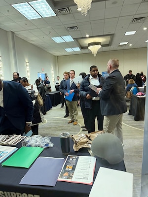 Photo shows a group of people standing in a conference room.