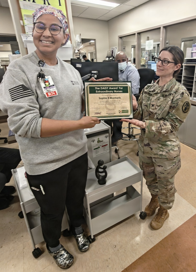 A nurse and an Army colonel pose with an an award.