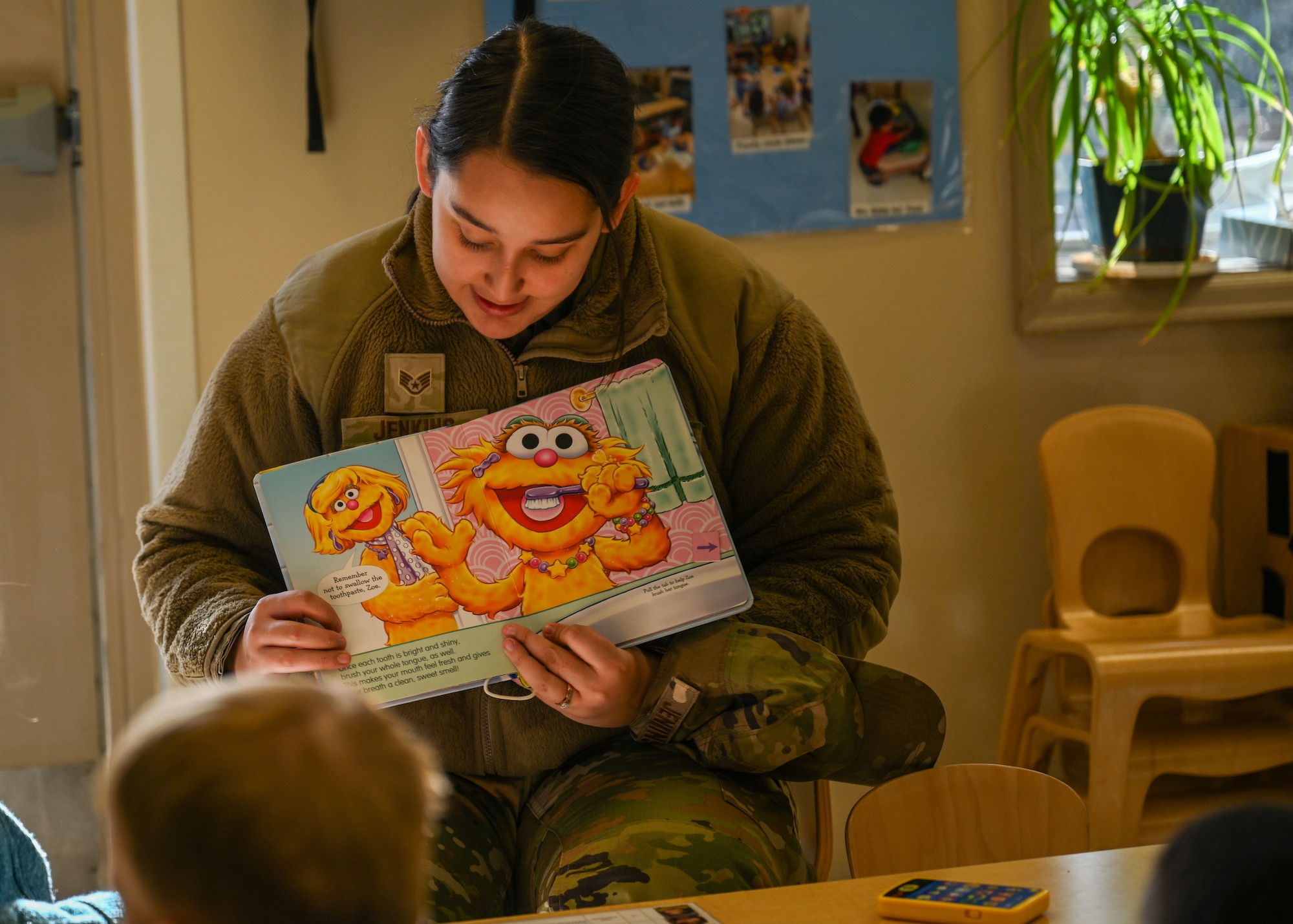 A servicemember reads a book to kids.